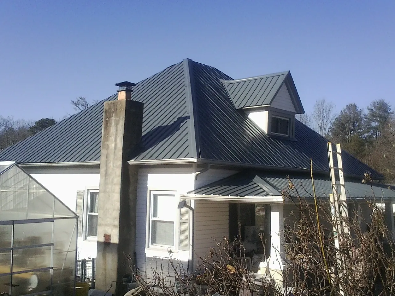 Dark blue standing seam metal roof on a white farmhouse with dormer — Slate & Tile Roof Repair by Roofing Brothers in West Hartford
