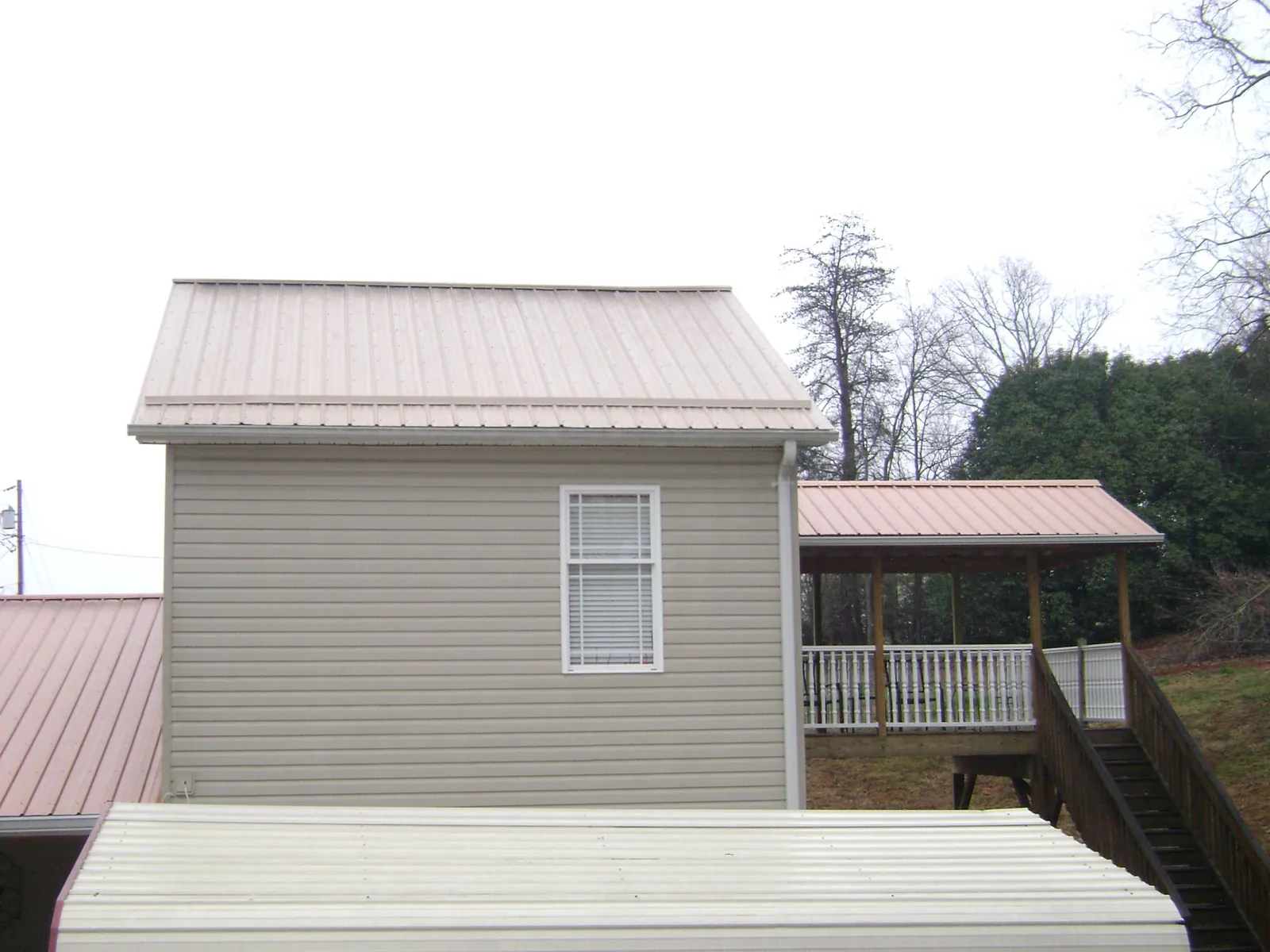 Tan metal roofs on a two story addition and attached porch, from a Roof Replacement job in West Hartford