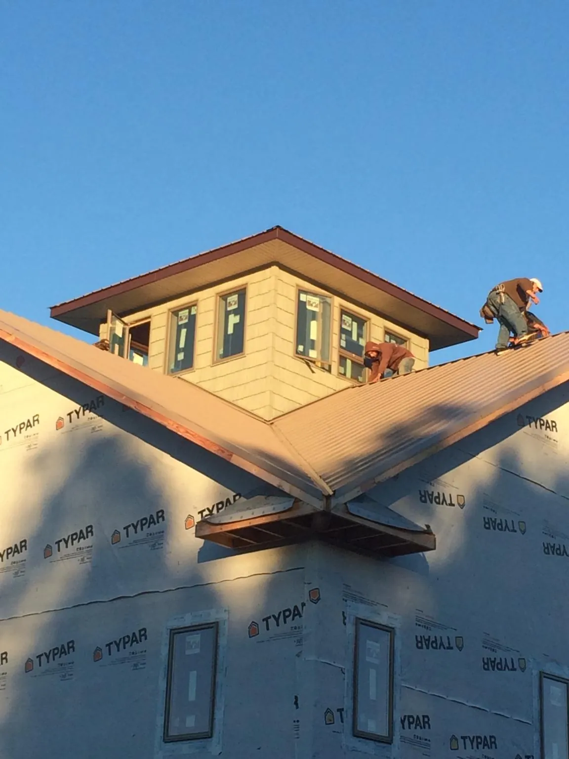 Roofers working around a rooftop cupola on a new metal roof at sunset — Roof Waterproofing in West Hartford by Roofing Brothers